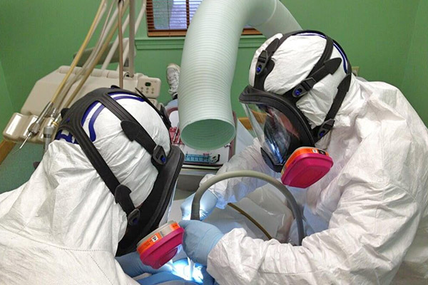 Dentists in protective gear while removing mercury fillings.